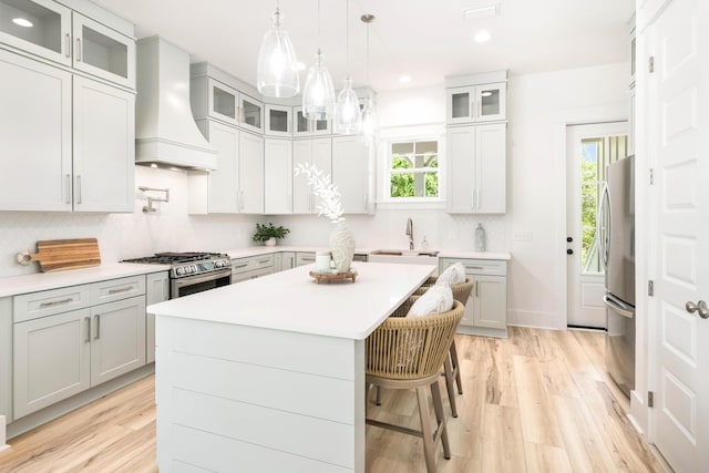 174 Grande Pointe Cir, Inlet Beach, FL 32461 - kitchen with custom range hood, backsplash, light countertops, a breakfast bar area, and light wood finished floors