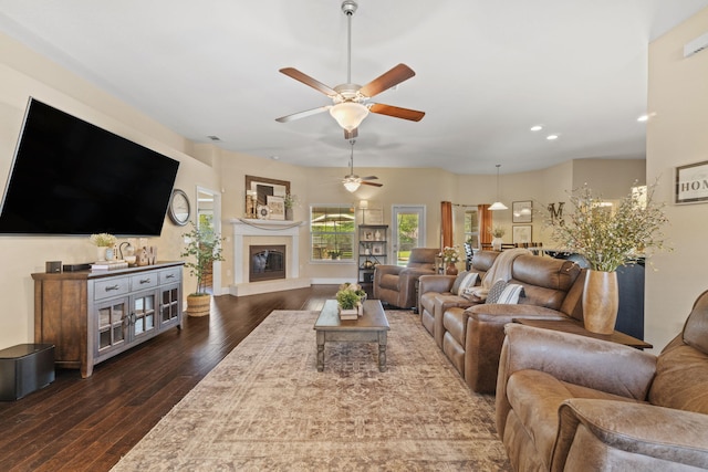 living area with a ceiling fan, dark wood finished floors, a glass covered fireplace, and recessed lighting