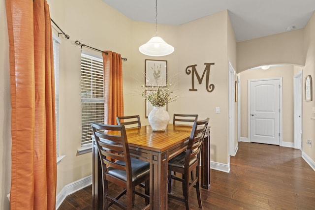 dining area featuring arched walkways, baseboards, and dark wood-style floors