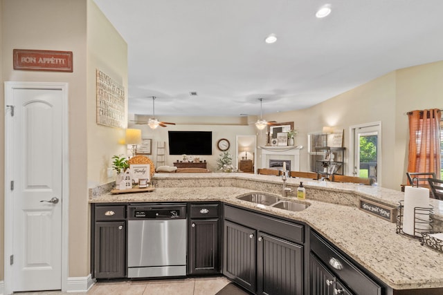 kitchen featuring stainless steel dishwasher, a sink, light stone countertops, open floor plan, and a ceiling fan