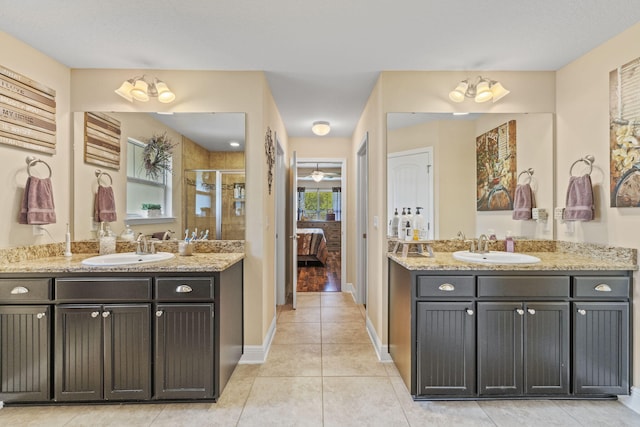 full bathroom featuring a sink, tile patterned floors, a shower stall, and two vanities