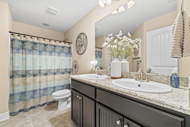 bathroom with a sink, tile patterned flooring, toilet, and double vanity