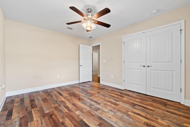 unfurnished bedroom featuring a ceiling fan, visible vents, wood finished floors, baseboards, and a closet