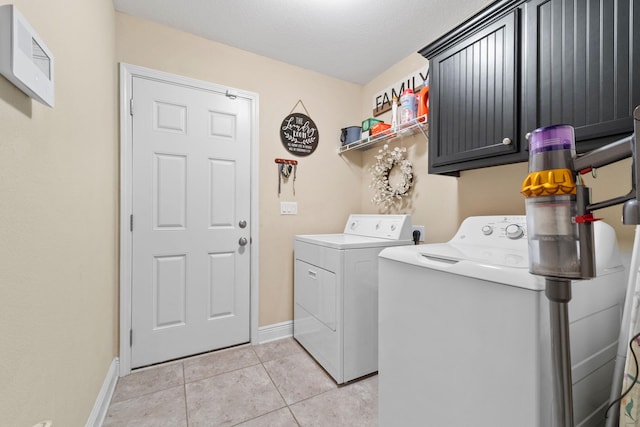 clothes washing area with light tile patterned floors, baseboards, cabinet space, and washing machine and clothes dryer