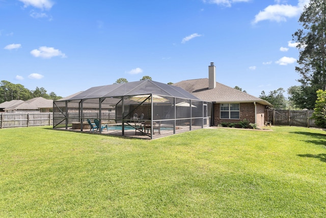 rear view of house with a yard, a fenced in pool, and a fenced backyard