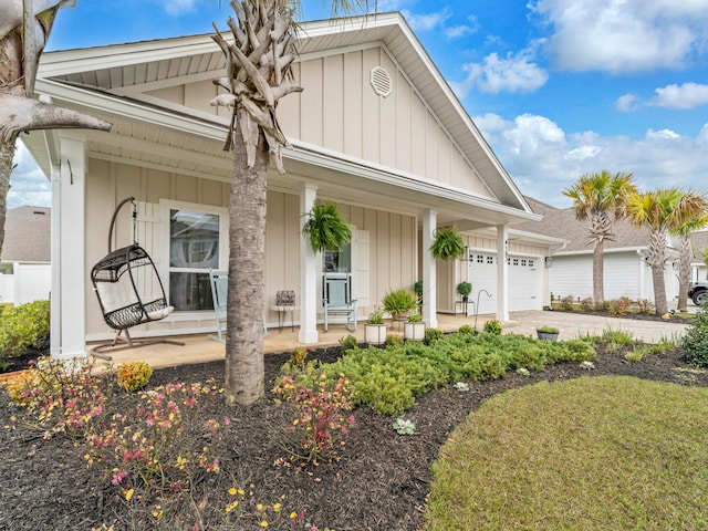 183 Pine Lake Dr, Santa Rosa Beach, FL 32459 - view of front of property with covered porch, board and batten siding, driveway, and a garage