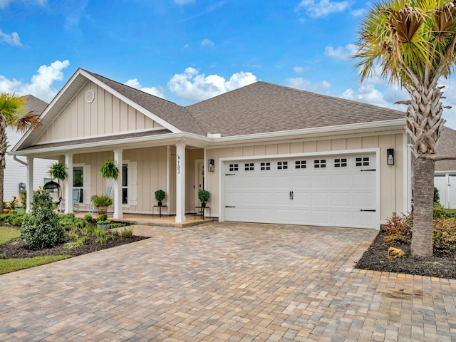 183 Pine Lake Dr, Santa Rosa Beach, FL 32459 - view of front facade featuring roof with shingles, a garage, board and batten siding, decorative driveway, and covered porch