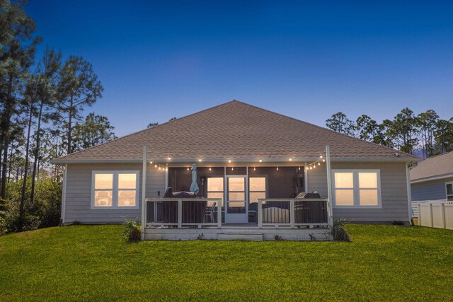 672 Alderberry Rd, Santa Rosa Beach, FL 32459 - back of house at dusk with a lawn, roof with shingles, and a sunroom