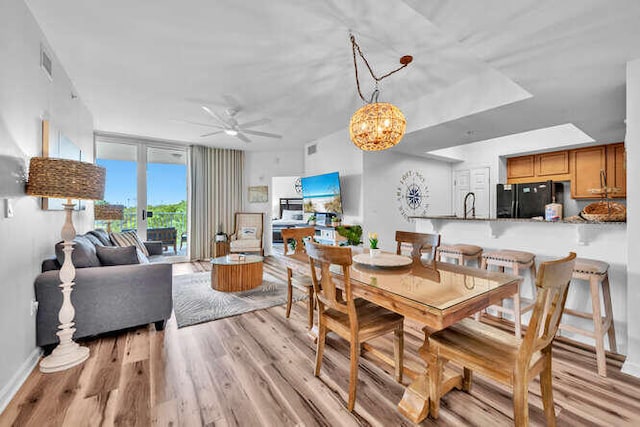 dining space featuring baseboards, a ceiling fan, light wood-type flooring, and visible vents