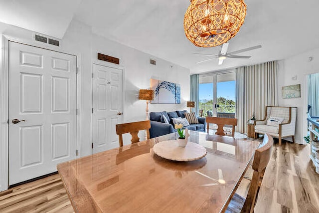 dining area featuring light wood-type flooring, ceiling fan with notable chandelier, and visible vents
