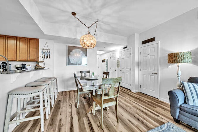 dining area with baseboards, an inviting chandelier, and light wood-style floors