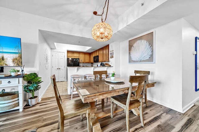 dining room with baseboards, a notable chandelier, and light wood-style floors