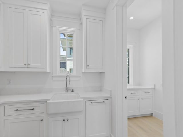 kitchen with recessed lighting, light countertops, white cabinetry, a sink, and light wood-style flooring