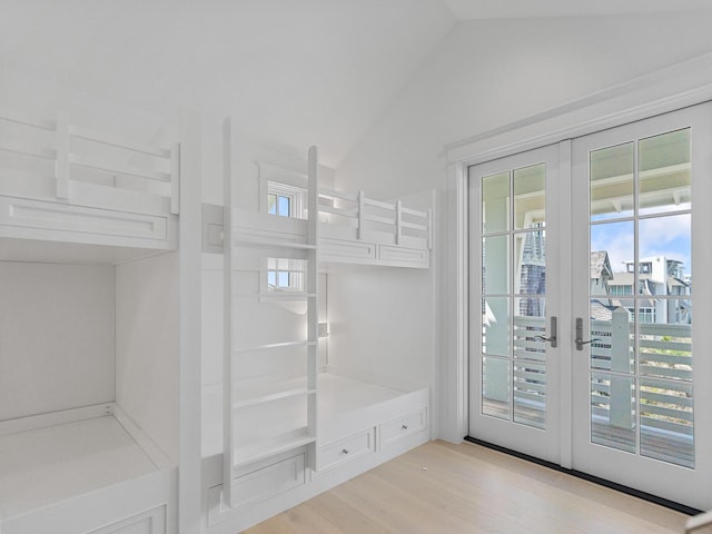 bathroom with french doors, lofted ceiling, and wood finished floors