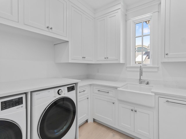 washroom with washer and dryer, light wood-style floors, a sink, and cabinet space