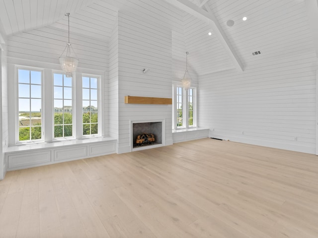 unfurnished living room featuring high vaulted ceiling, a healthy amount of sunlight, and light wood-type flooring