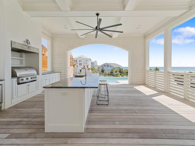 deck with grilling area, ceiling fan, exterior kitchen, a sink, and a water view