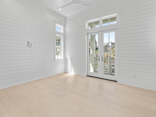 empty room with french doors, wood walls, and wood finished floors