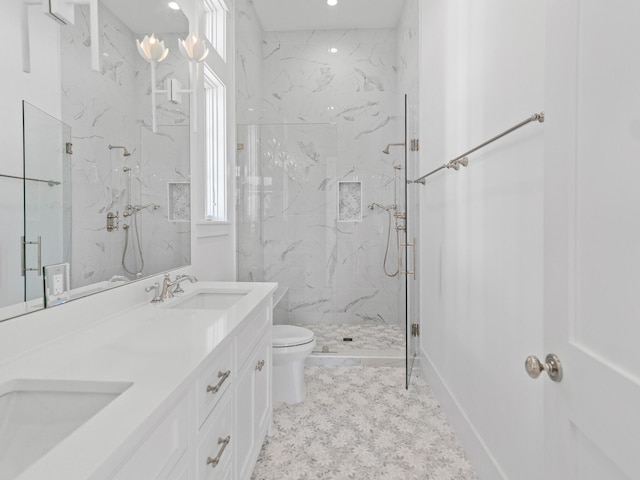 bathroom with double vanity, toilet, a marble finish shower, and a sink