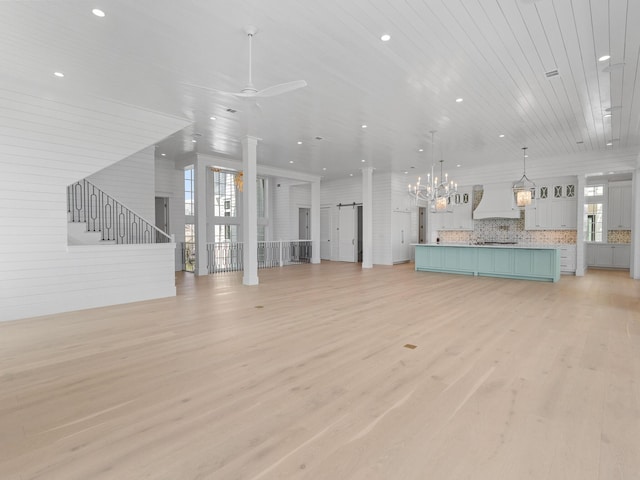 unfurnished living room featuring stairs, light wood-style floors, ceiling fan, recessed lighting, and a barn door