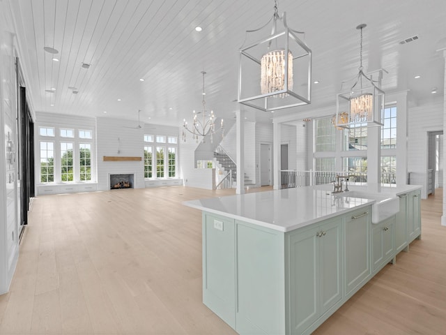 kitchen featuring visible vents, a fireplace, a spacious island, an inviting chandelier, and light wood-style flooring