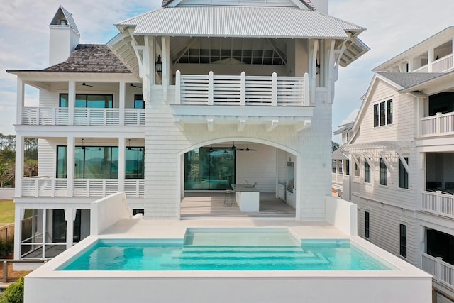 rear view of property with a patio, ceiling fan, a balcony, and an outdoor pool