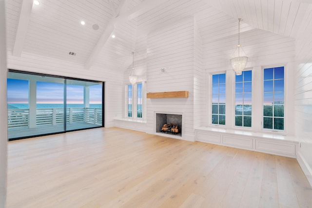 unfurnished living room featuring wood finished floors, a wealth of natural light, high vaulted ceiling, and a large fireplace