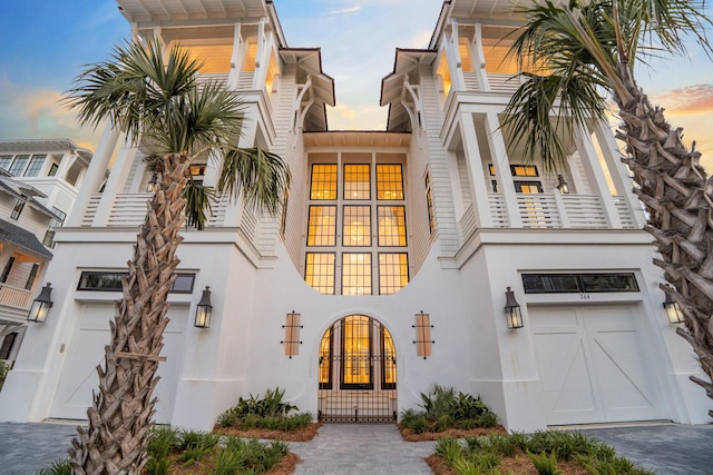 view of front of home with stucco siding, an attached garage, driveway, and a balcony