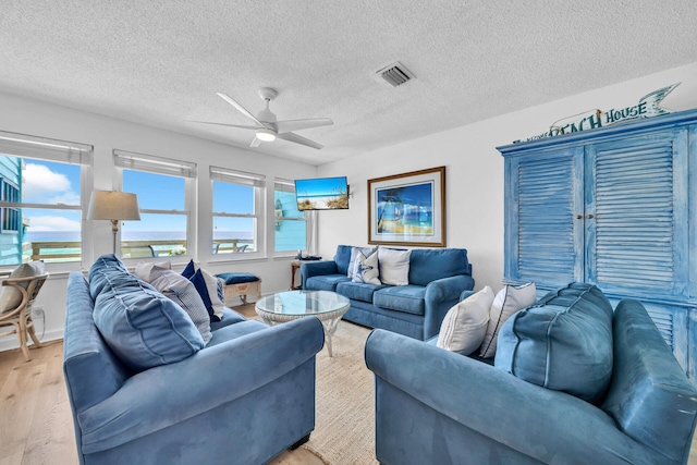 living area featuring a textured ceiling, visible vents, wood finished floors, and a ceiling fan