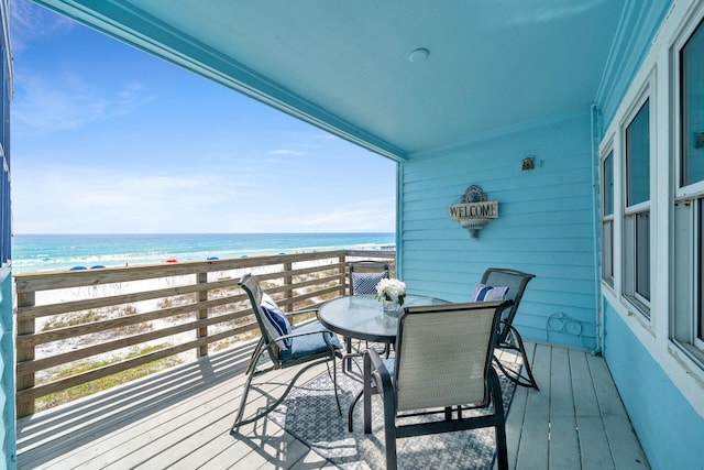 balcony with a view of the beach, outdoor dining area, and a water view