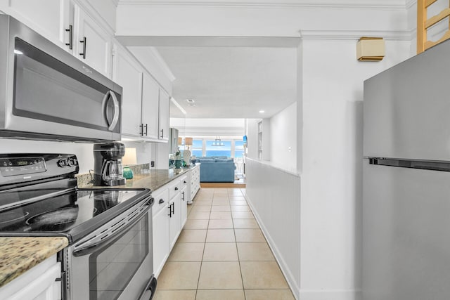 kitchen with stainless steel appliances, light stone counters, white cabinetry, light tile patterned floors, and baseboards
