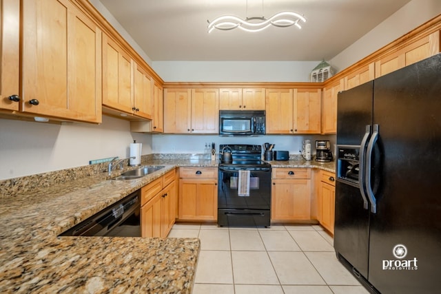 kitchen featuring light stone countertops, a sink, light tile patterned floors, black appliances, and light brown cabinets