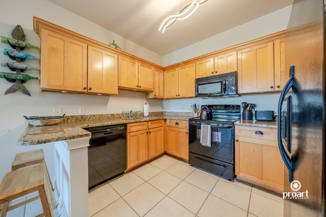 kitchen with light brown cabinetry, light stone countertops, black appliances, and a peninsula