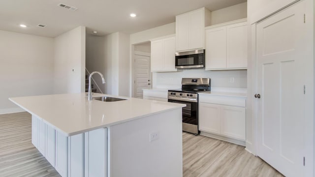 3068 Heritage Plantation Blvd, Laurel Hill, FL 32567 - kitchen with a kitchen island with sink, visible vents, a sink, light wood-style floors, and stainless steel appliances