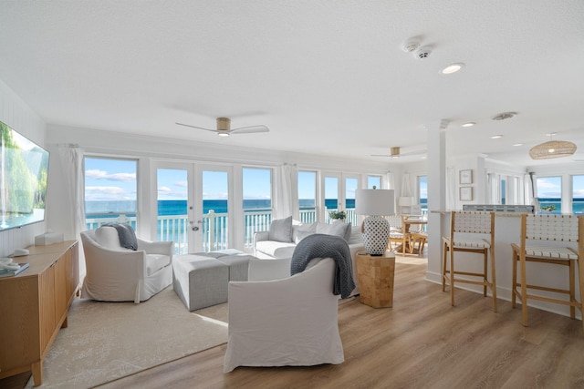 living room with light wood-style flooring, ceiling fan, and a healthy amount of sunlight