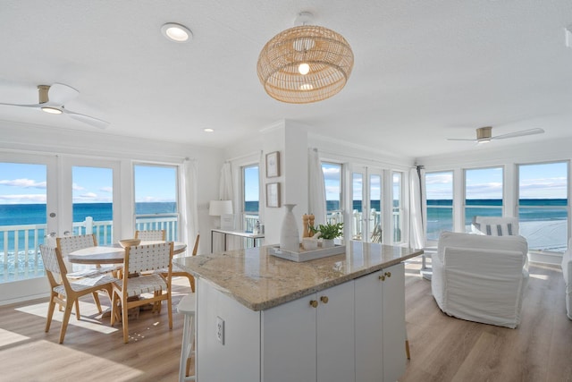 kitchen featuring a water view, light wood-style flooring, ceiling fan, and a kitchen island