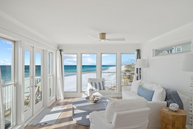 sunroom featuring french doors, a view of the beach, and a water view