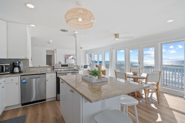 kitchen with light wood-style floors, appliances with stainless steel finishes, a center island, and a water view