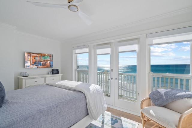 bedroom featuring a ceiling fan, ornamental molding, a water view, access to outside, and light wood-style flooring