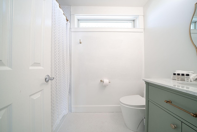 bathroom with vanity, baseboards, tile patterned flooring, and toilet