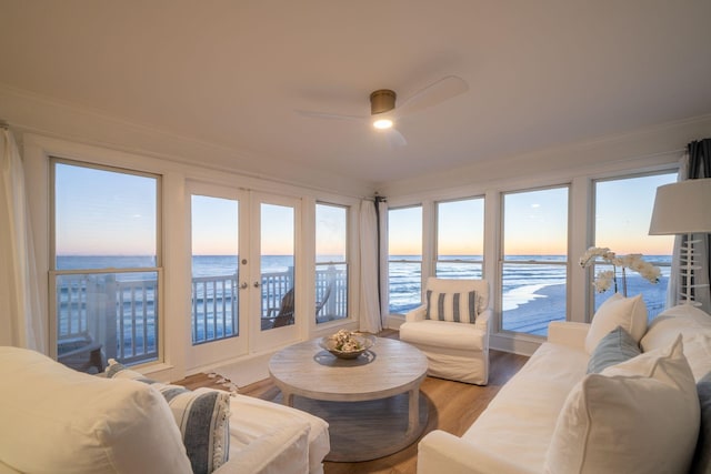 living room featuring a ceiling fan, a water view, and ornamental molding