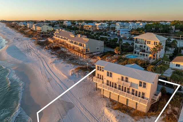 aerial view at dusk with a beach view, a residential view, and a water view