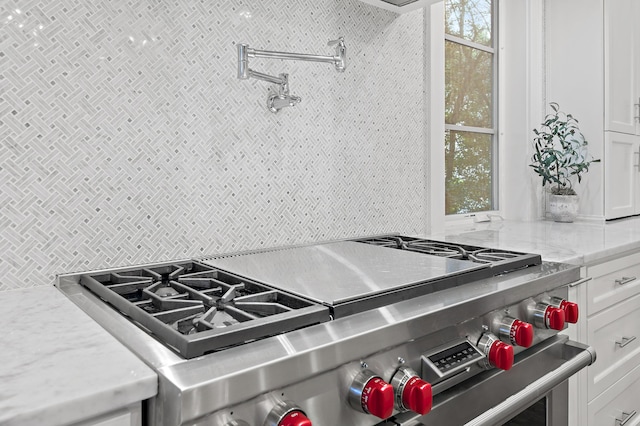 489 Regatta Bay Blvd, Destin, FL 32541 - kitchen featuring high end stainless steel range, backsplash, healthy amount of natural light, and white cabinetry