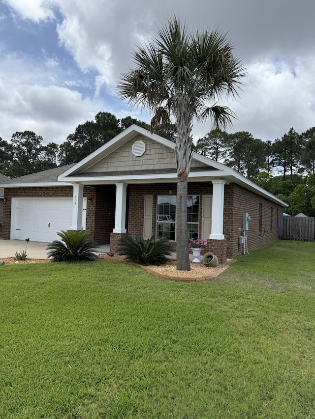 view of front of property featuring brick siding, fence, a front yard, and a garage