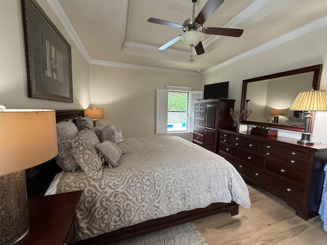 bedroom with crown molding, a ceiling fan, a tray ceiling, and light wood-style floors