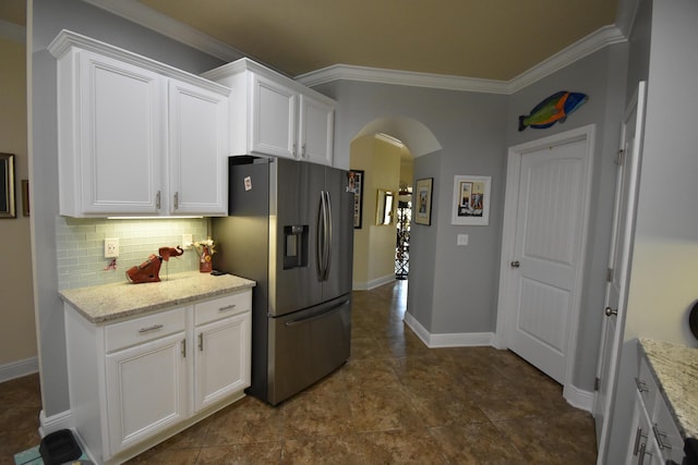 kitchen with crown molding, white cabinetry, stainless steel fridge with ice dispenser, arched walkways, and backsplash