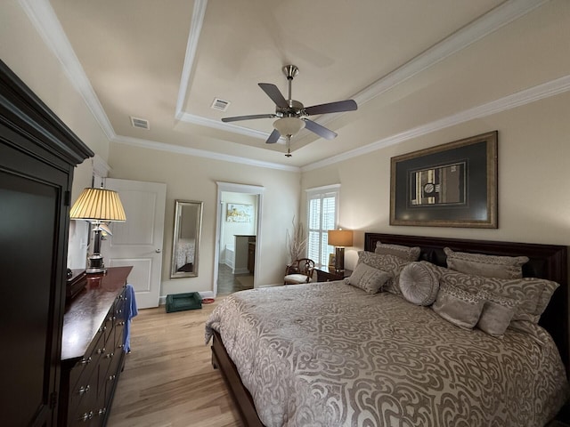 bedroom featuring a raised ceiling, ornamental molding, light wood-type flooring, and visible vents