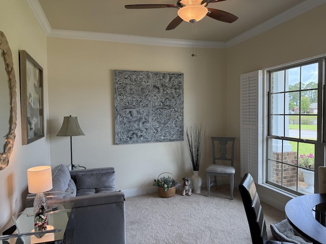 living area with crown molding, carpet flooring, baseboards, and ceiling fan