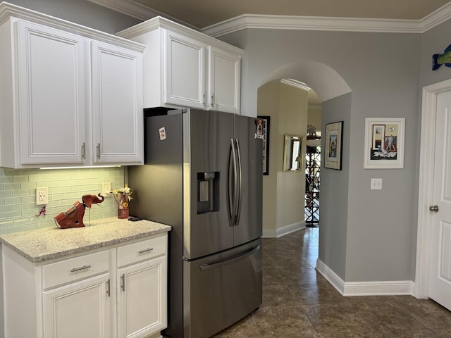 kitchen featuring white cabinets, arched walkways, stainless steel fridge with ice dispenser, and tasteful backsplash