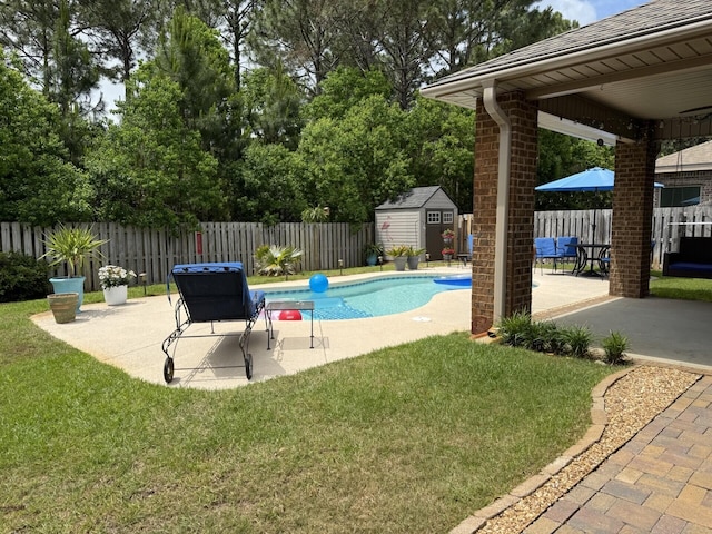 view of pool with a lawn, a patio, a fenced backyard, and a storage unit